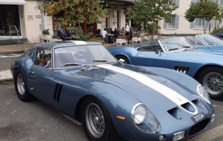 Blue sports car with white stripes, parked in front of a café.