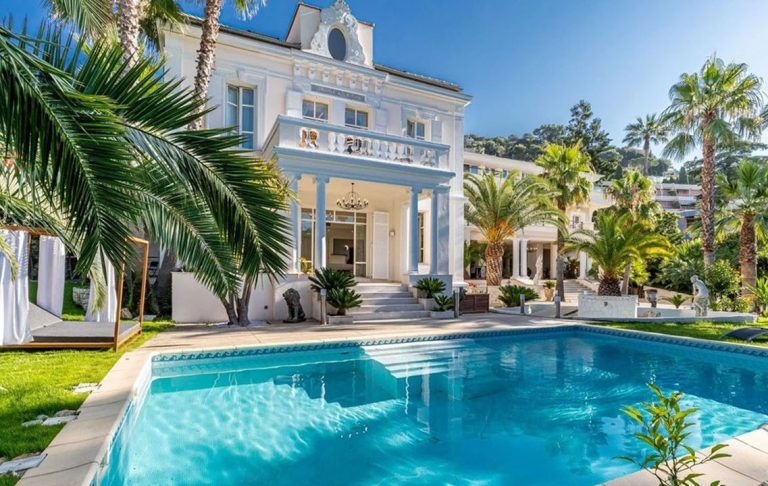 Elegant villa with swimming pool, surrounded by palm trees and greenery.