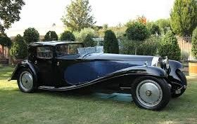 Antique car, dark blue in color, parked on a lawn.