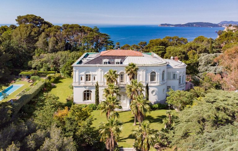 White villa surrounded by palm trees, with sea view and swimming pool.