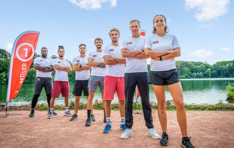 A group of six people in sportswear near a lake, preparing for an activity.
