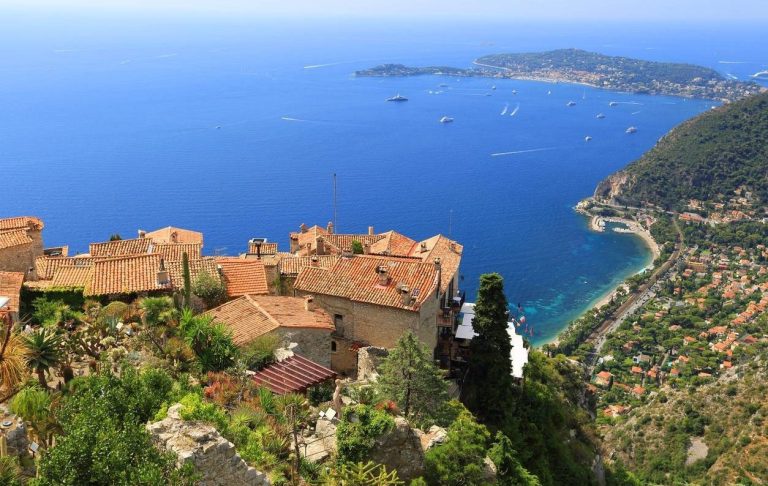 Village perched on a cliff overlooking the azure sea and verdant coastline.