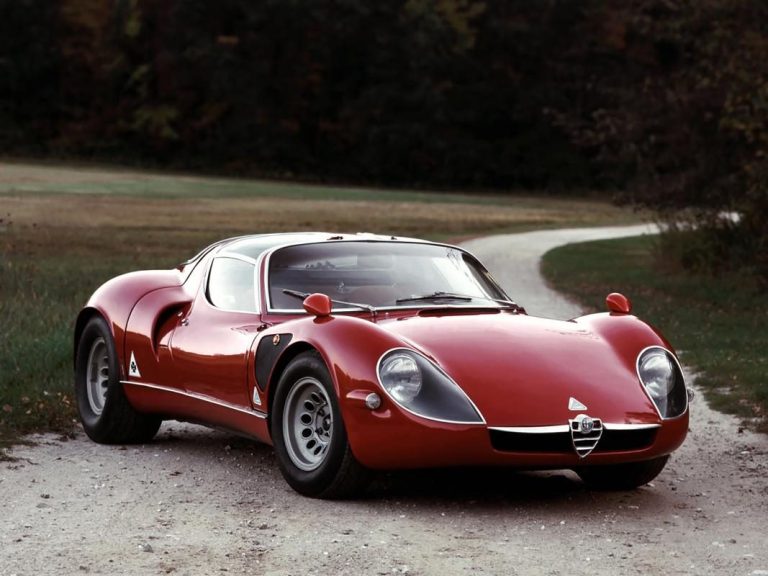 Red sports car in vintage design, parked on a winding road in the countryside.