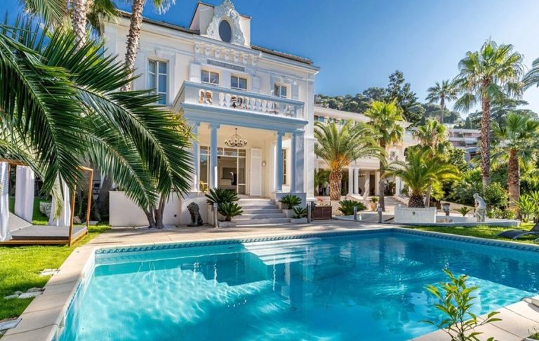 Elegant villa with swimming pool, surrounded by palm trees and lush greenery.