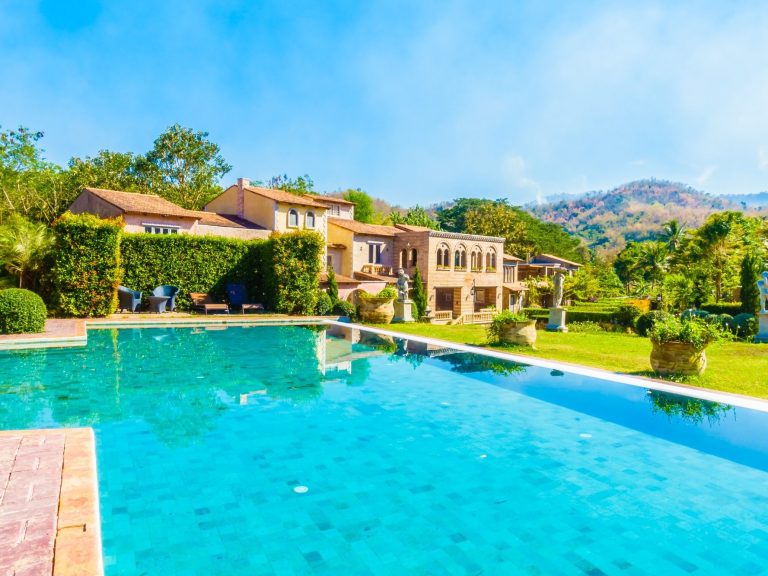 Villa with pool and lush garden, set against a backdrop of rolling hills.