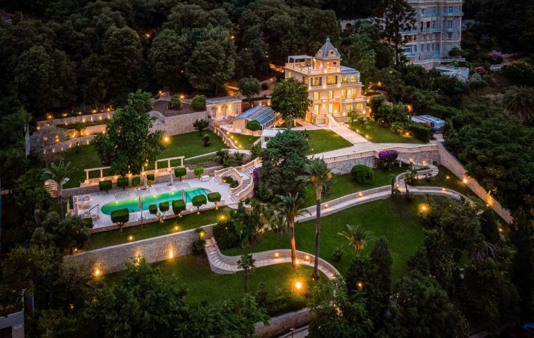 Aerial view of a villa with swimming pool surrounded by illuminated gardens.