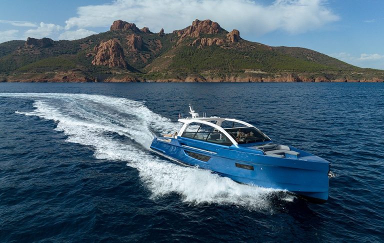 Fast boat at sea with mountains in background and partly cloudy sky.